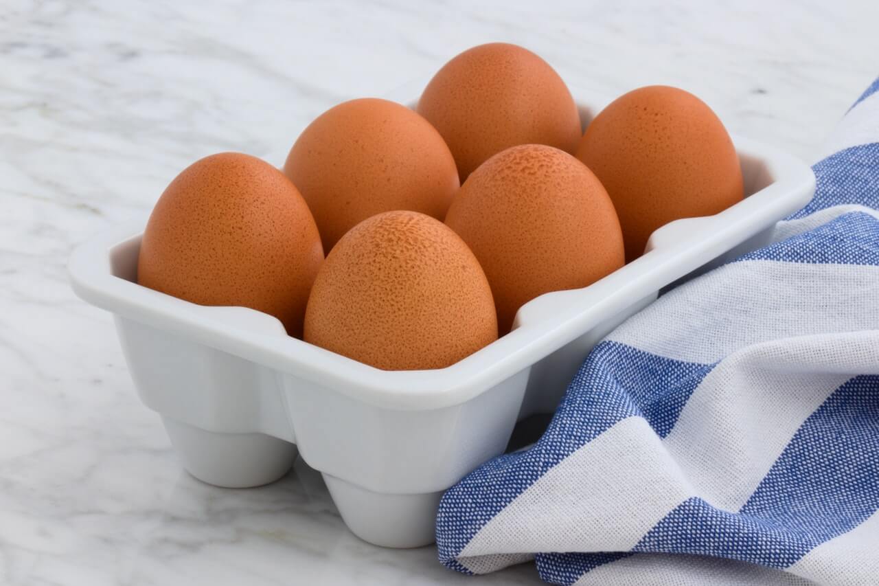 Six brown eggs in a container on a counter