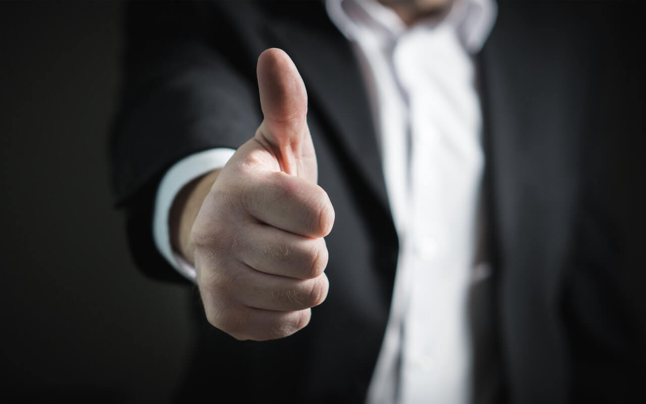 Man in suit giving thumbs up saying yes