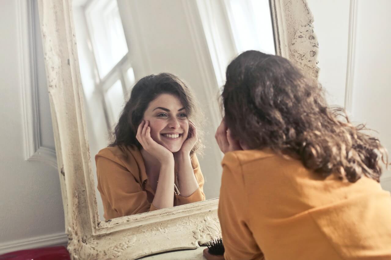 Happy woman smiling at herself in the mirror