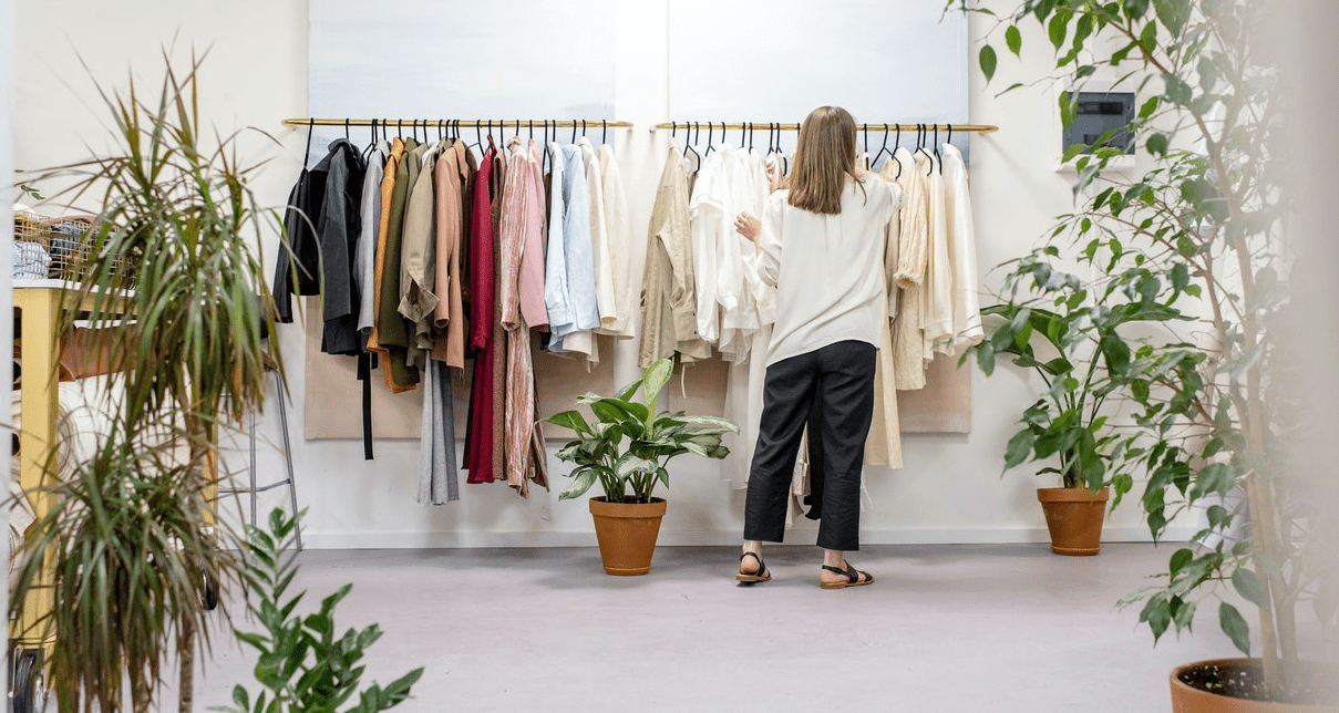 Woman standing in front of a clothes rail with clothes organised by colour