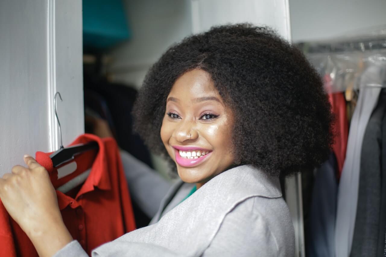 Woman smiling and taking out a red blouse from a wardrobe