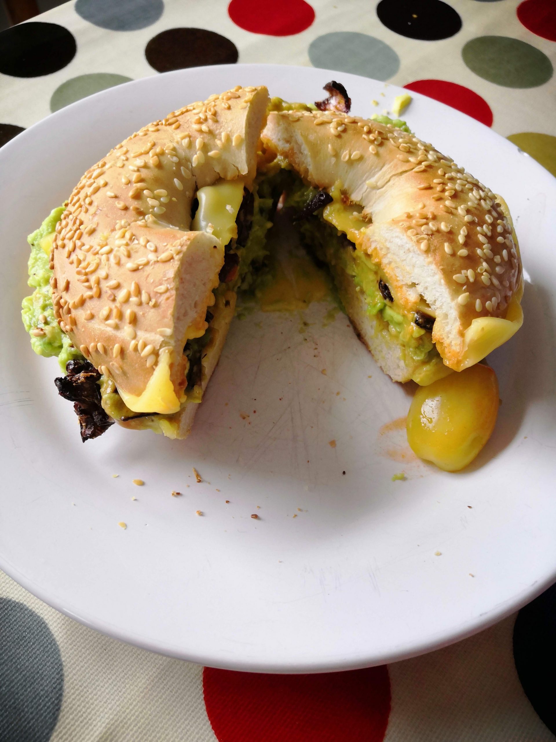 Vegan avocado, lettuce, tomato and cheese bagel on a plate