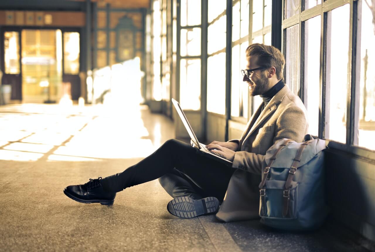 Man sitting on floor looking at online content on laptop