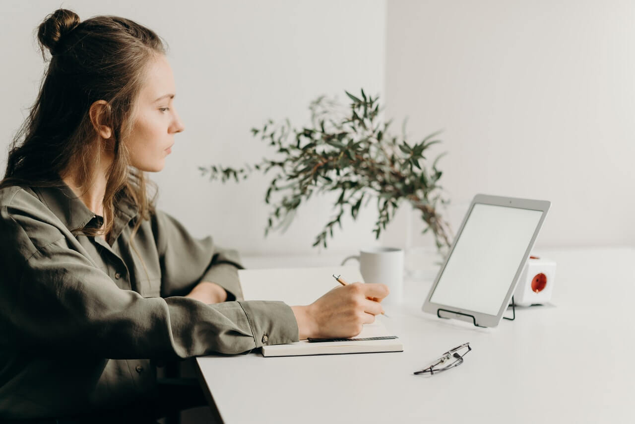 Woman sitting at desk with book and tablet